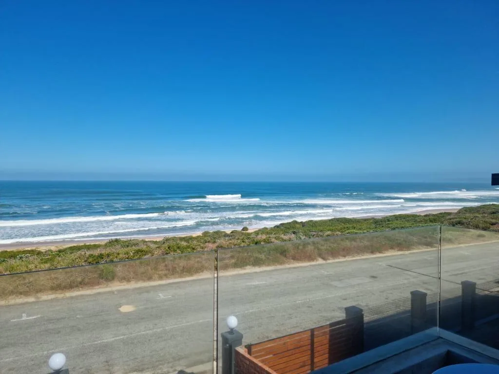 Expansive ocean view with white sandy beach and rolling waves from property deck