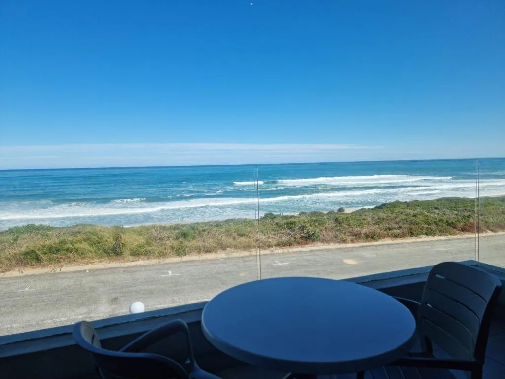 Ocean and beach view from elevated deck with coastal vegetation below