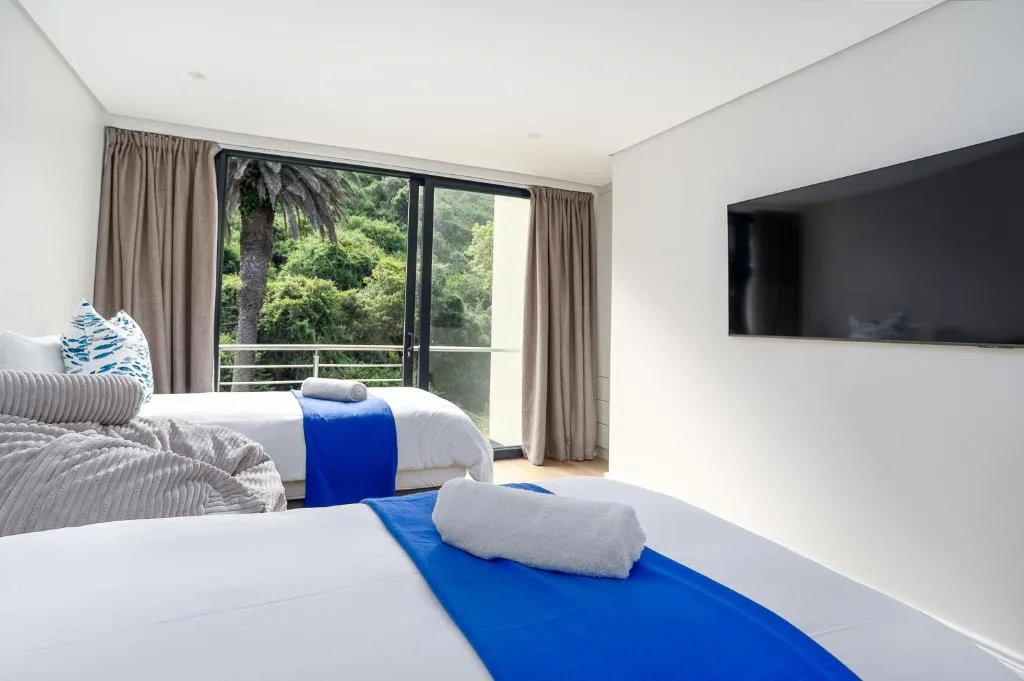 Bright bedroom with twin beds, lush garden views through sliding doors