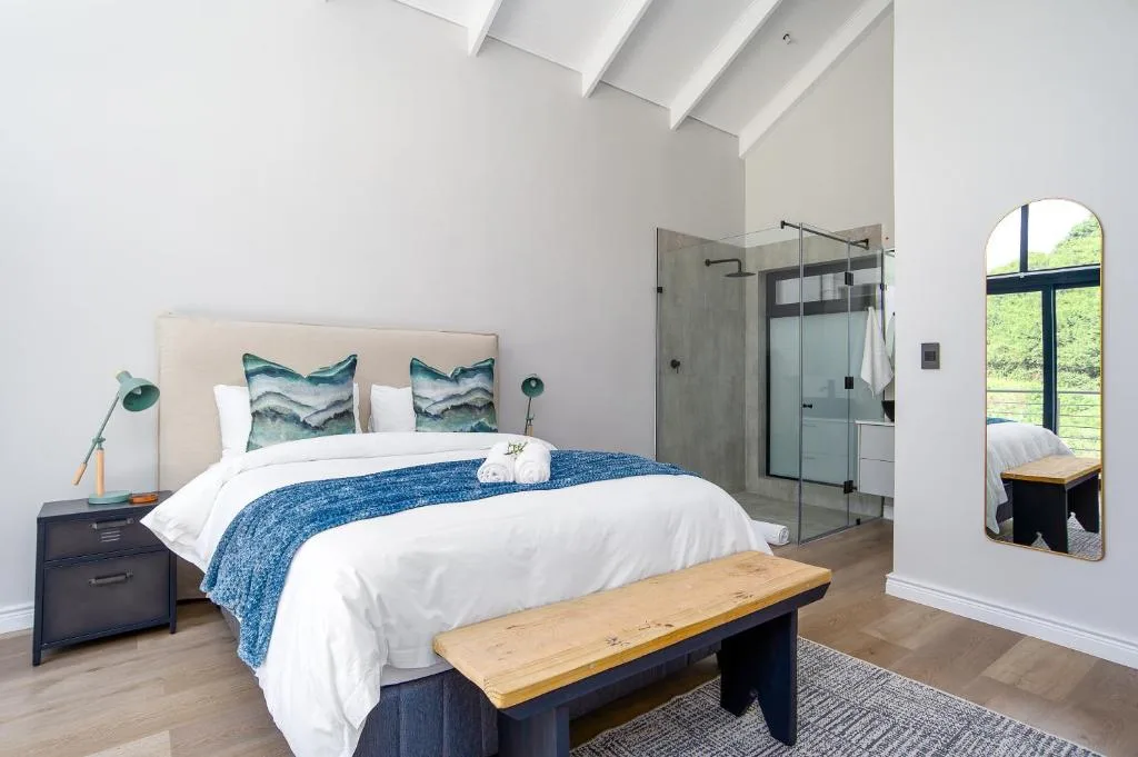 Bright bedroom with queen bed, ensuite bathroom, and garden views