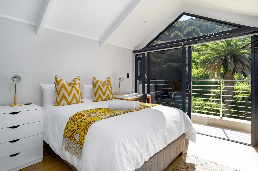 Bright bedroom with queen bed, yellow accents, and garden views through sliding doors