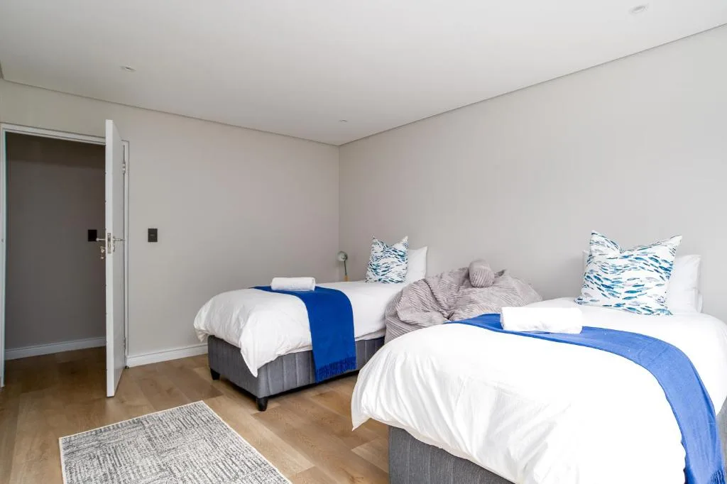 Bright bedroom with two twin beds, white linens, and blue accents