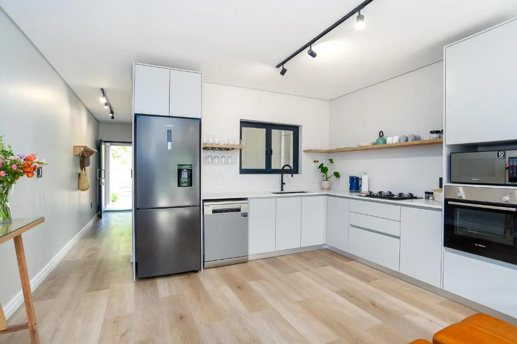 Modern white kitchen with stainless steel appliances and wooden flooring