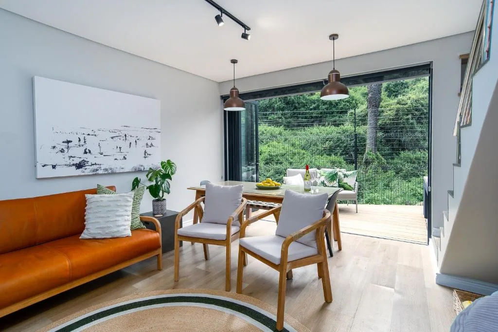 Modern lounge with orange sofa, wooden chairs, and large sliding doors opening to deck