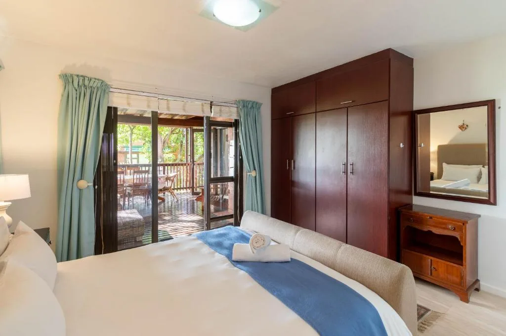 Spacious bedroom with queen bed, dark wood wardrobe, and deck access