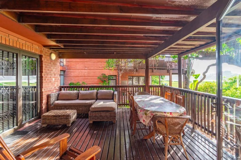 Covered wooden deck with wicker seating and outdoor dining table