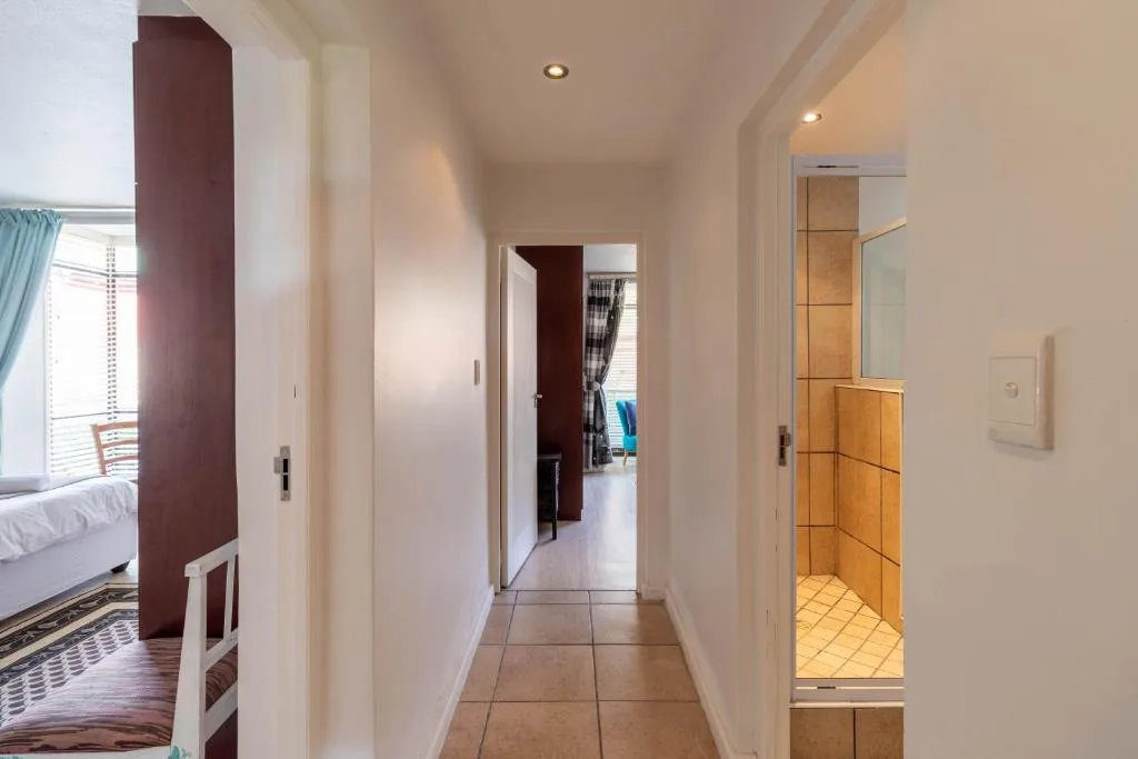 Modern hallway with tiled flooring, burgundy accent wall, and bedroom access
