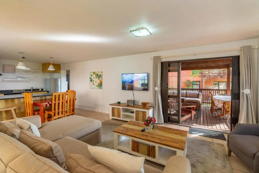 Open-plan lounge with comfortable seating, TV, and deck access