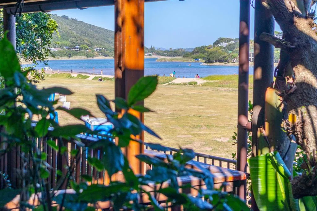 Scenic beach and lagoon view from shaded deck with green foliage