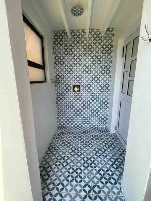 Shower room with geometric patterned floor tiles and overhead rainfall showerhead