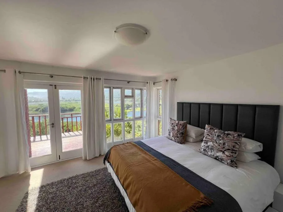 Bright bedroom with black headboard, valley views through glass doors to deck