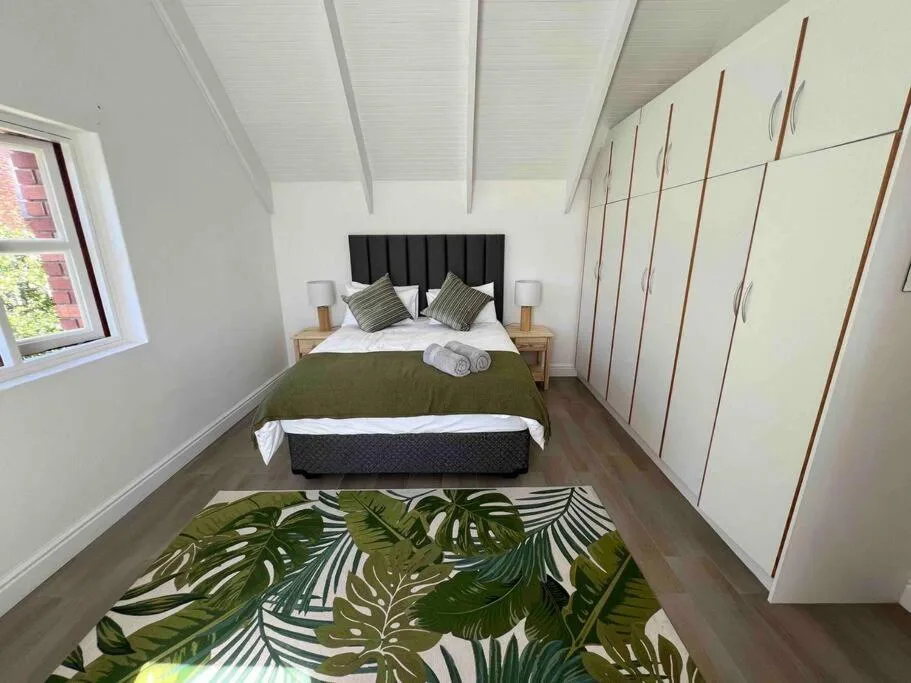 Bright bedroom with queen bed, black headboard, and built-in wardrobes