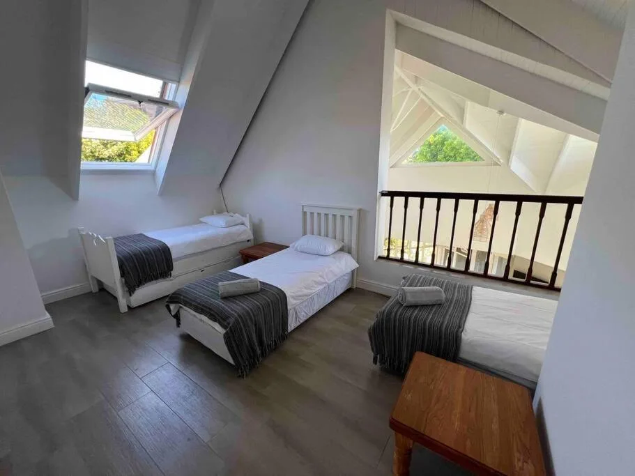 Bright attic bedroom with three single beds and views through windows