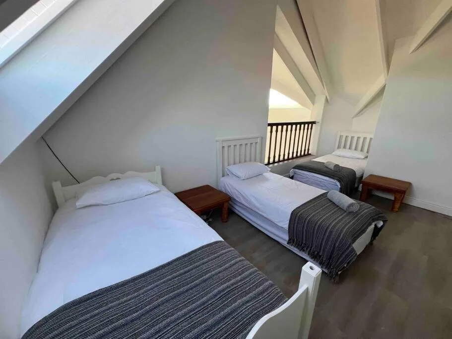 Bright attic bedroom with two single beds and white railings overlooking space