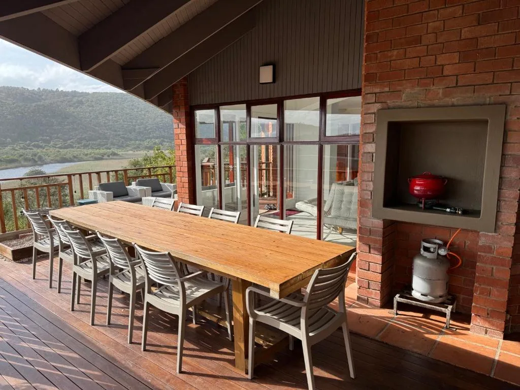 Covered deck with wooden dining table, chairs, and lagoon views