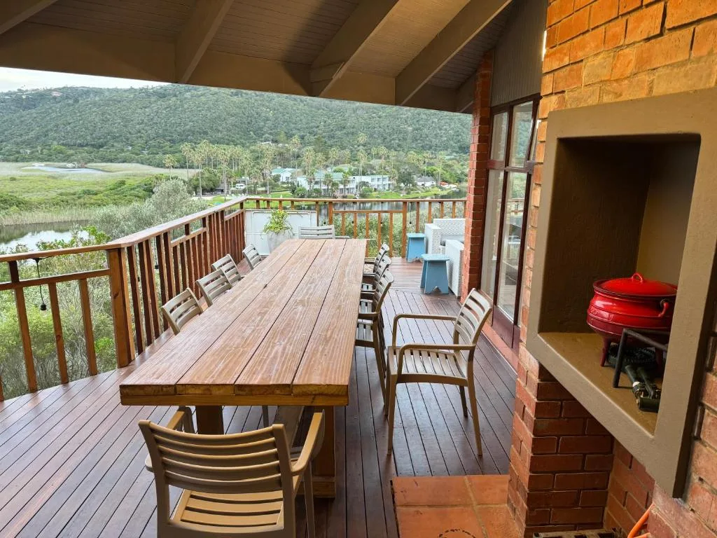 Spacious wooden deck with dining table overlooking river and lush mountains