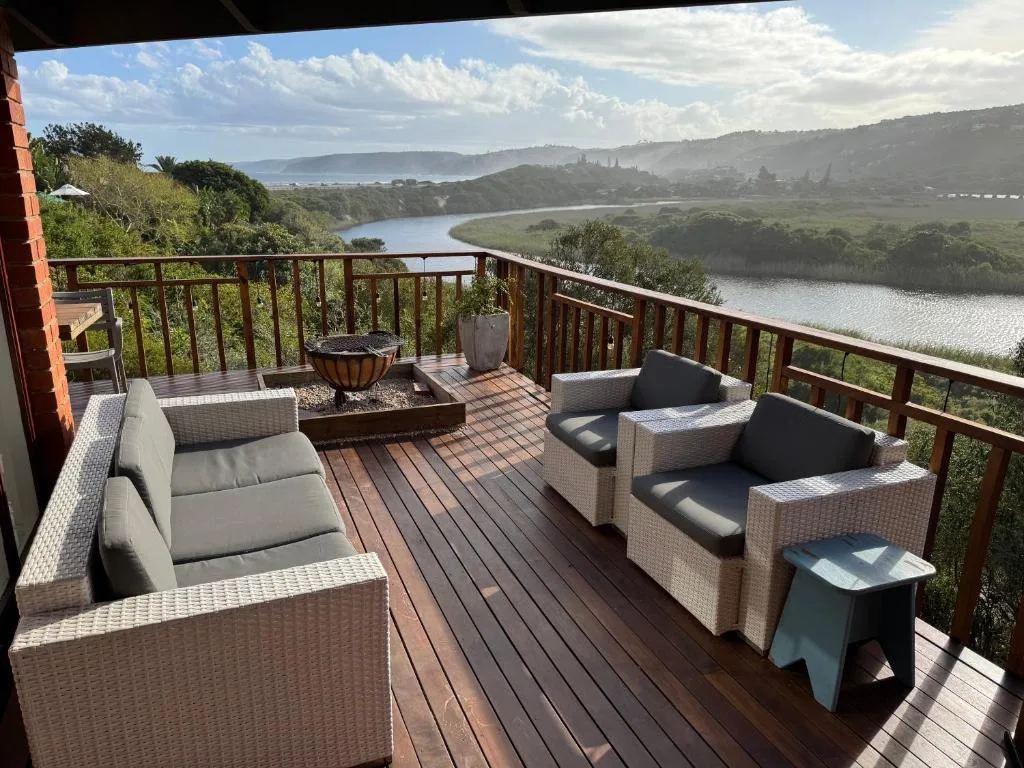Spacious wooden deck with wicker seating overlooking lagoon and mountains