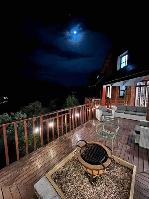 Illuminated wooden deck with braai, seating, and moonlit night sky views