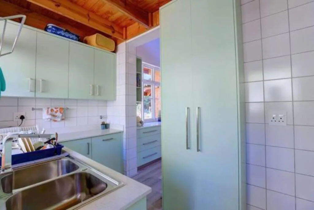 Modern kitchen with mint cabinetry, stainless steel sink, and wooden ceiling beams
