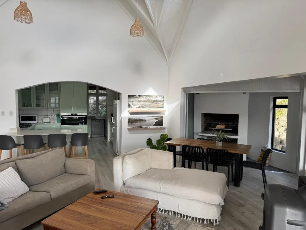 Open-plan lounge with cream sofas, fireplace, and ocean artwork on walls