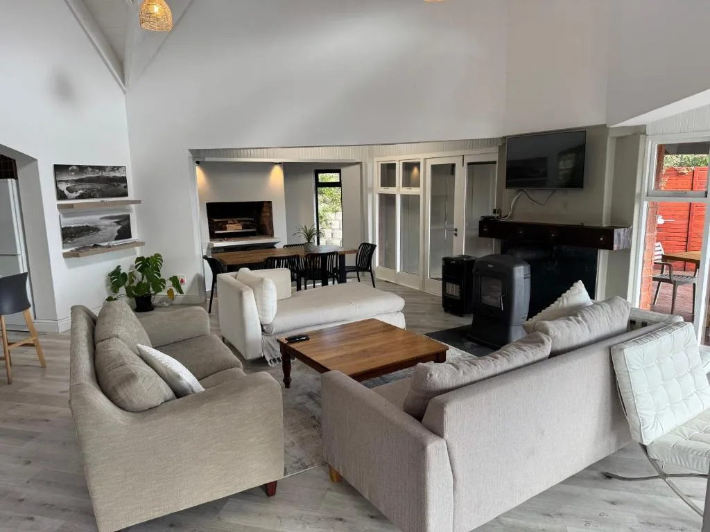 Open-plan lounge with cream sofas, wooden coffee table, and fireplace