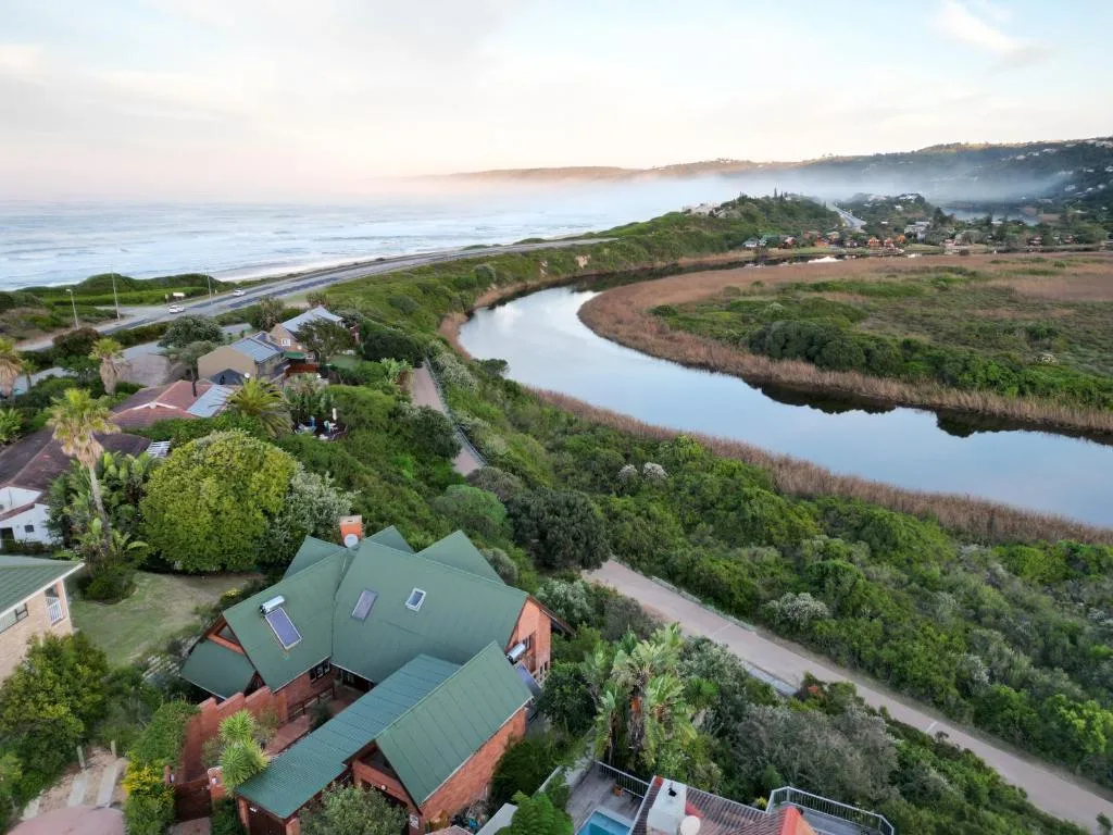 Aerial view of property overlooking lagoon, ocean, and misty coastal hills