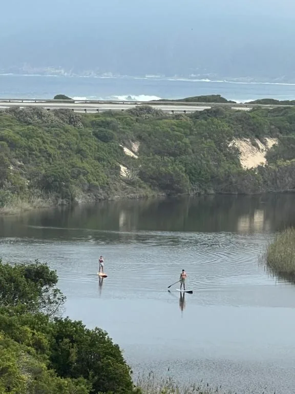 Scenic lagoon view with paddleboarders and dramatic green cliffs beyond