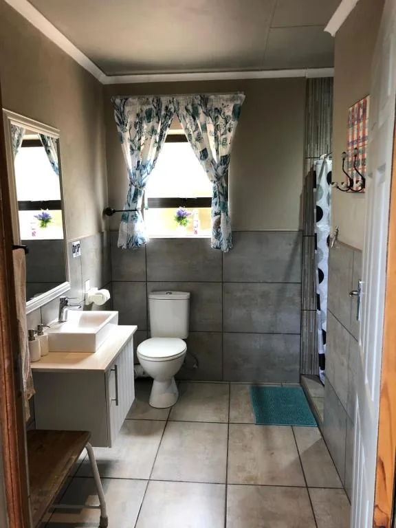 Modern bathroom with grey tile, white vanity, toilet, and shower enclosure