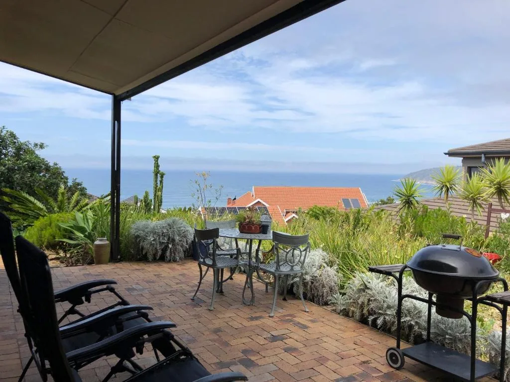 Covered patio with braai, seating, and ocean views beyond