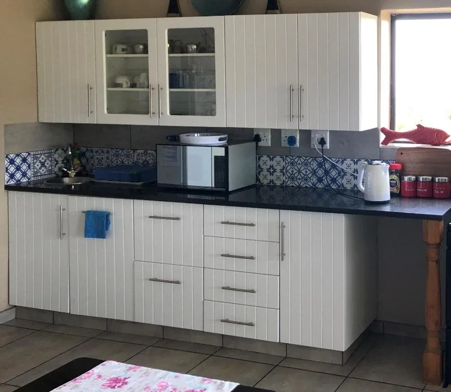 Modern white kitchen with black countertop, appliances, and patterned backsplash