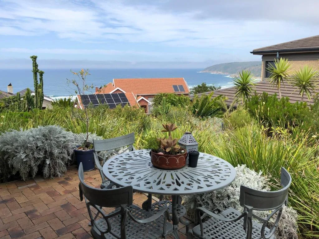 Coastal landscape with ocean, cliffs, and beachfront homes visible from garden