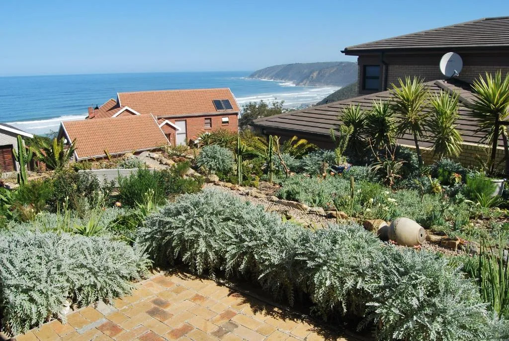 Ocean coastline and cliffs visible beyond landscaped property gardens