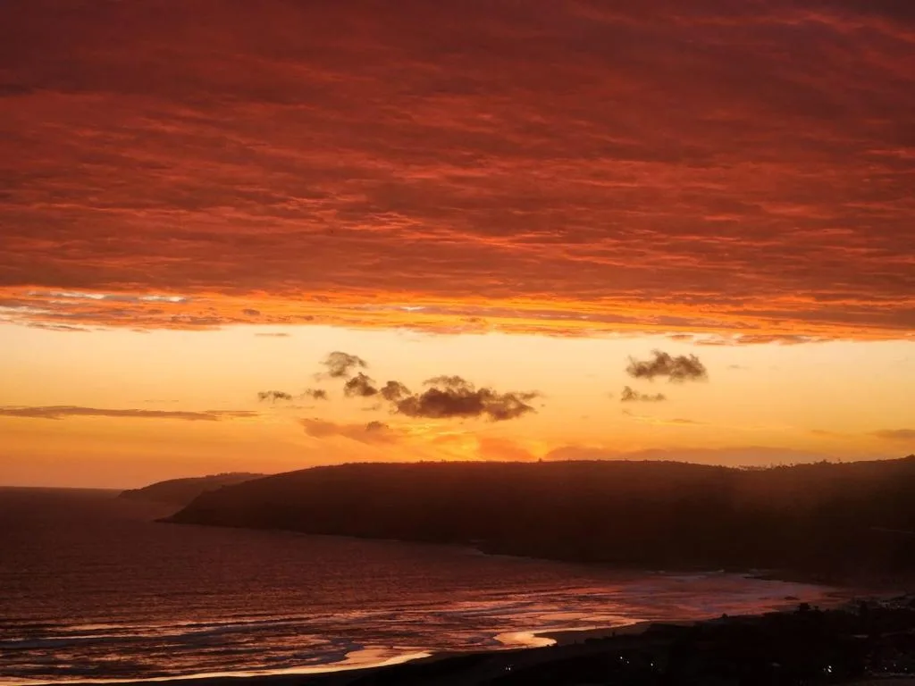 Dramatic sunset over ocean and cliffs with golden sky