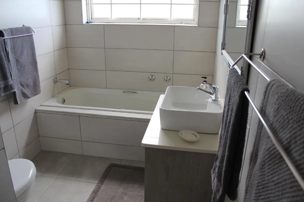 Clean bathroom with bathtub, sink, toilet, and large window