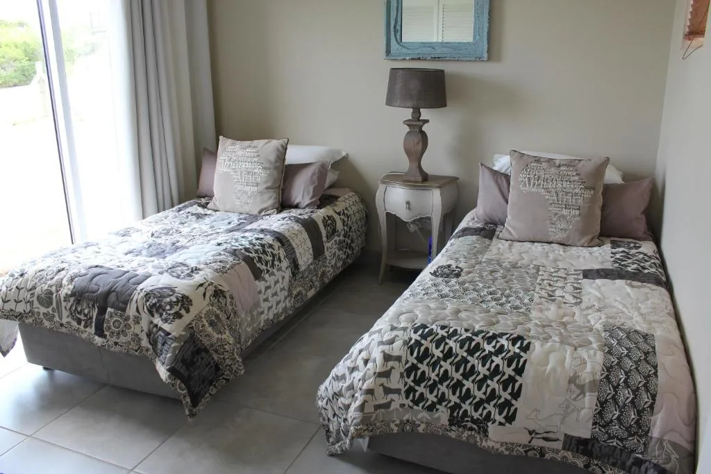 Twin bedroom with patterned quilts, decorative pillows, and bedside lamp